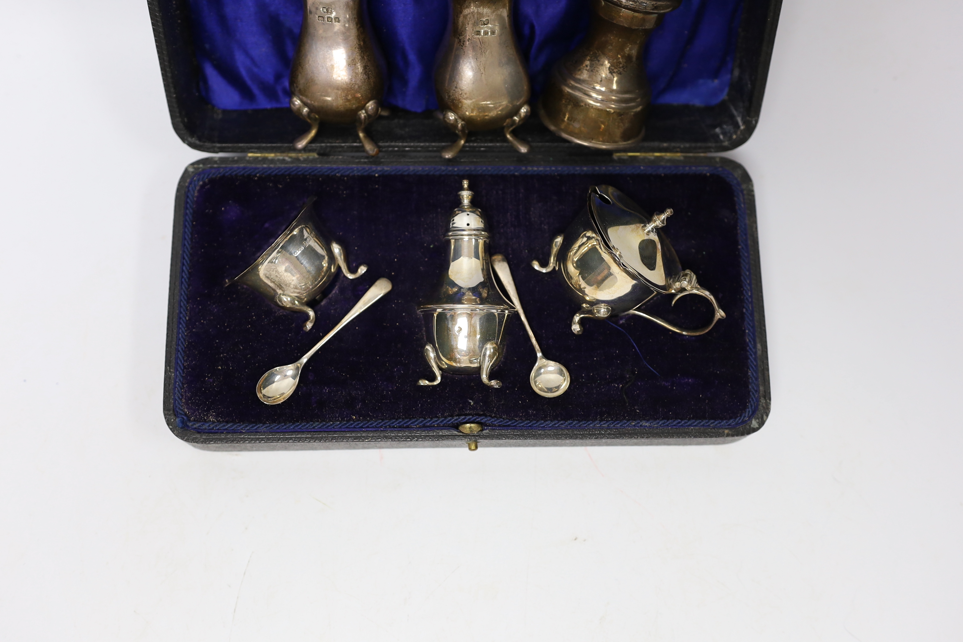 A cased George V silver three piece condiment set, Birmingham, 1919, a pair of later silver pepperettes and a silver mounted pepper mill.
